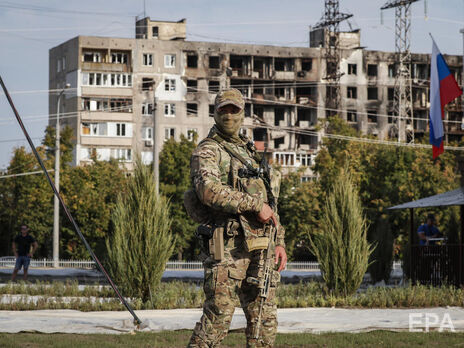 Російський військовий на тлі зруйнованого будинку