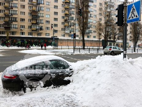 В Киеве коммунальщики засыпали снегом припаркованный Porsche. Фоторепортаж